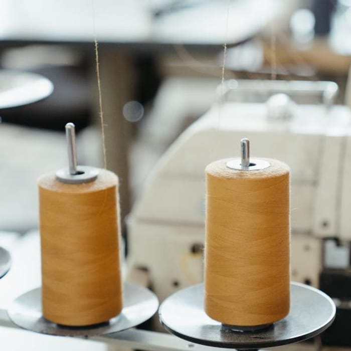 Industrial sewing machines with thread cones on a knitwear stitching line